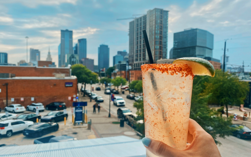 cocktail on a rooftop patio with view of Downtown Dallas, Texas