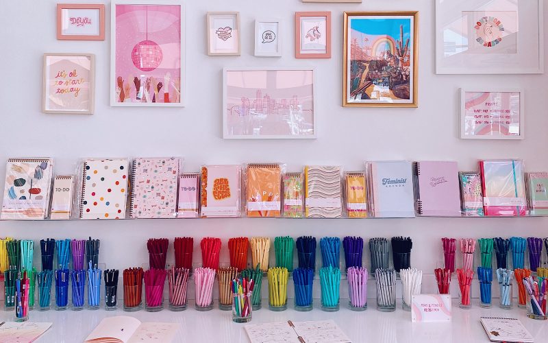 brightly colored pens arrange in front of a variety of pastel art work