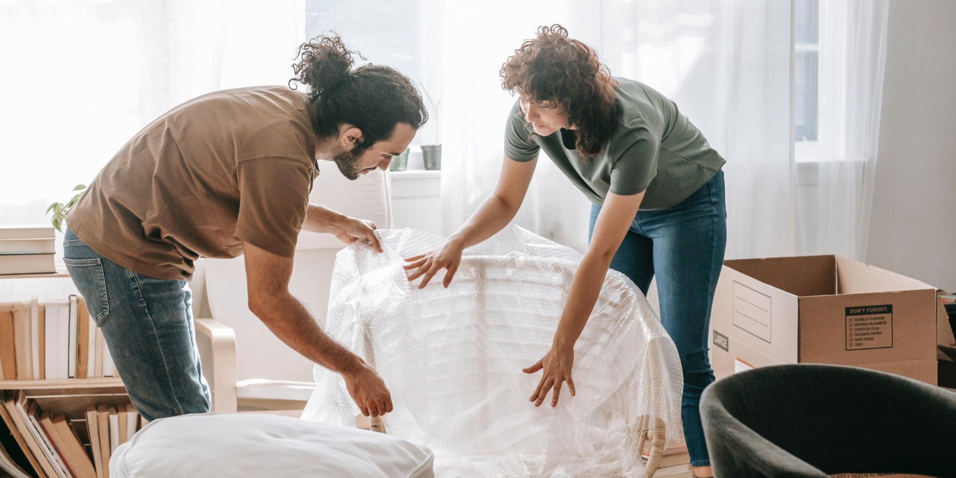 couple packing up an apartment using bubble wrap