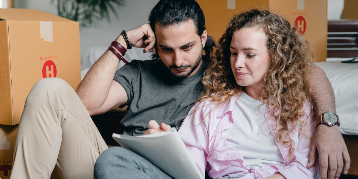 A couple sitting on a couch looking at a notebook