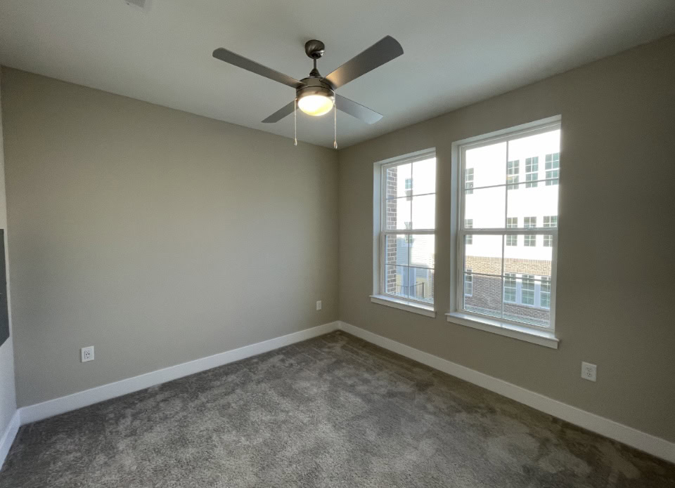 Upper Westside apartment bedroom with large windows and carpeted flooring.