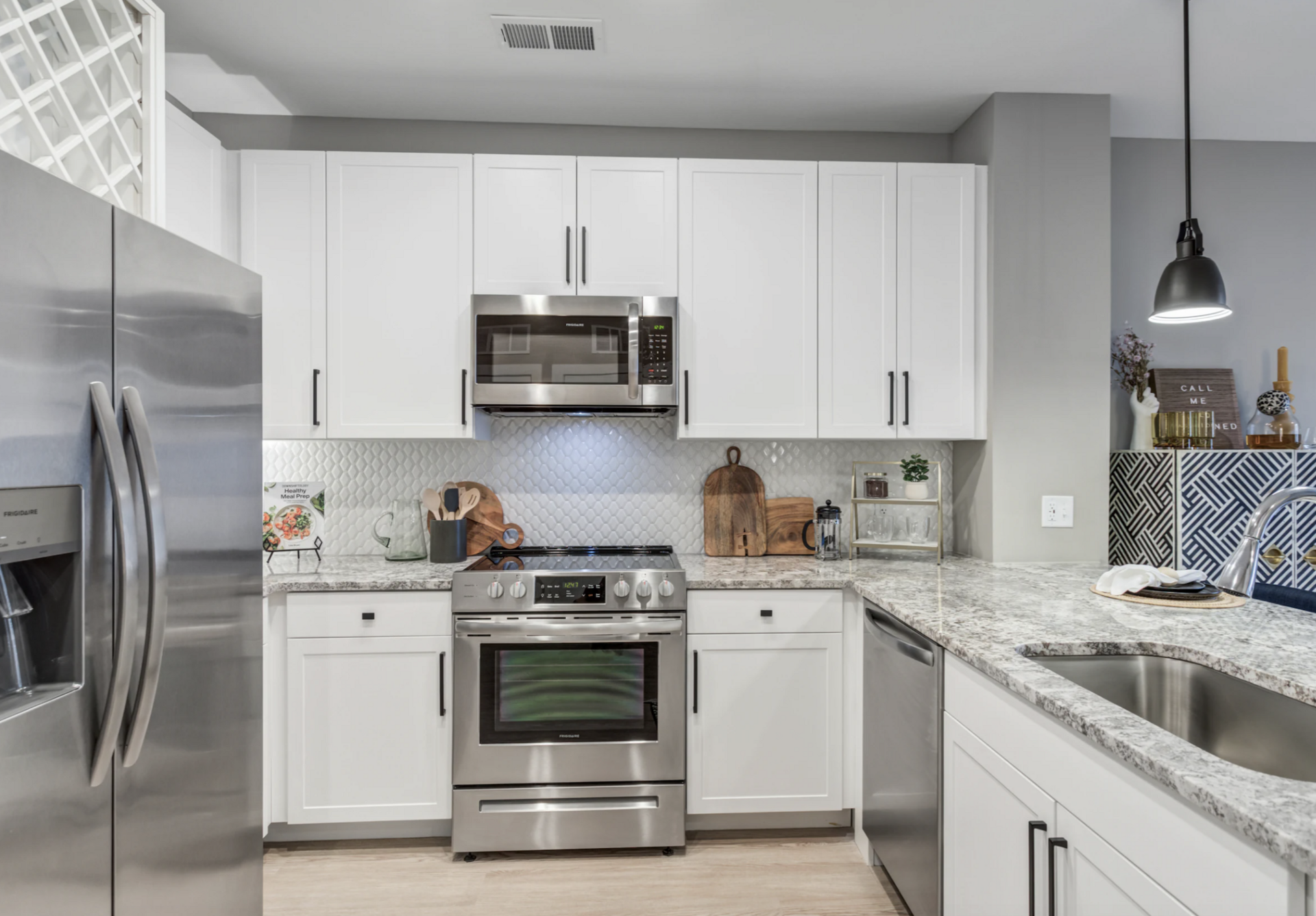 Nashville Midtown apartment kitchen with white cabinets and black hardware.