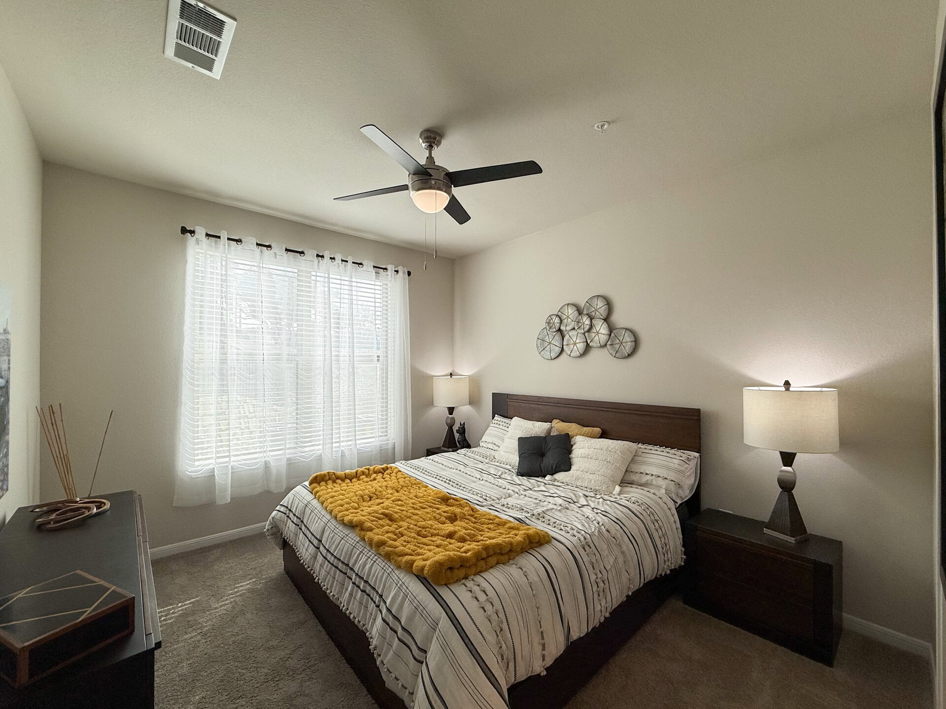 A cozy bedroom features a queen-sized bed with beautiful natural light.