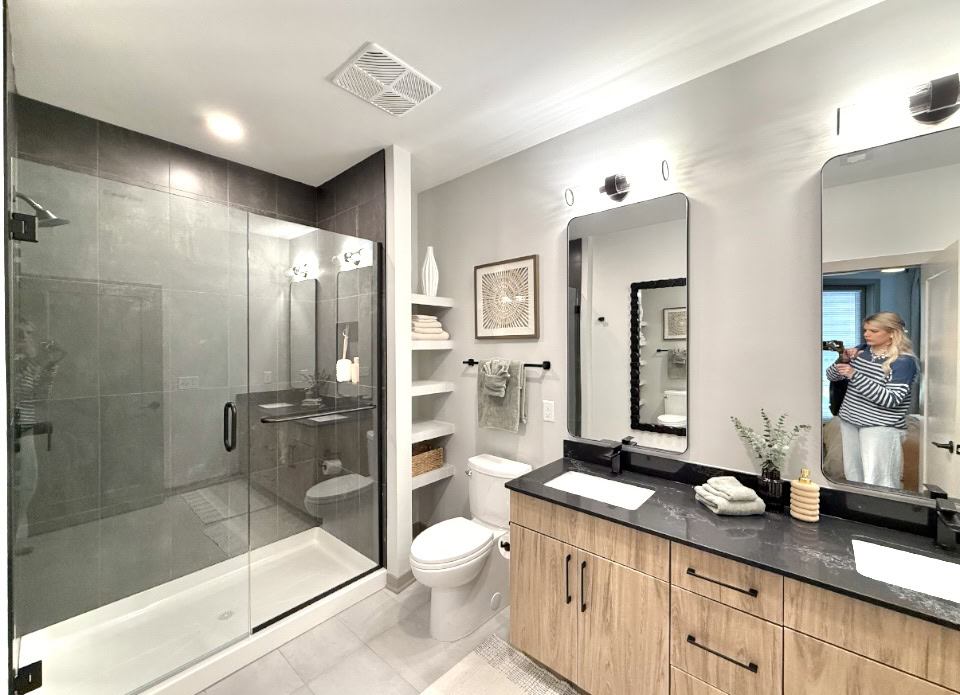 Downtown Nashville apartment bathroom with dark finishes, a double vanity, and large walk in shower.