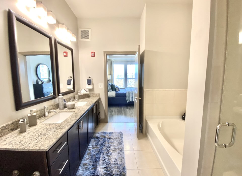 Buckhead apartment bathroom with dual vanities, and a shower + tub combo.