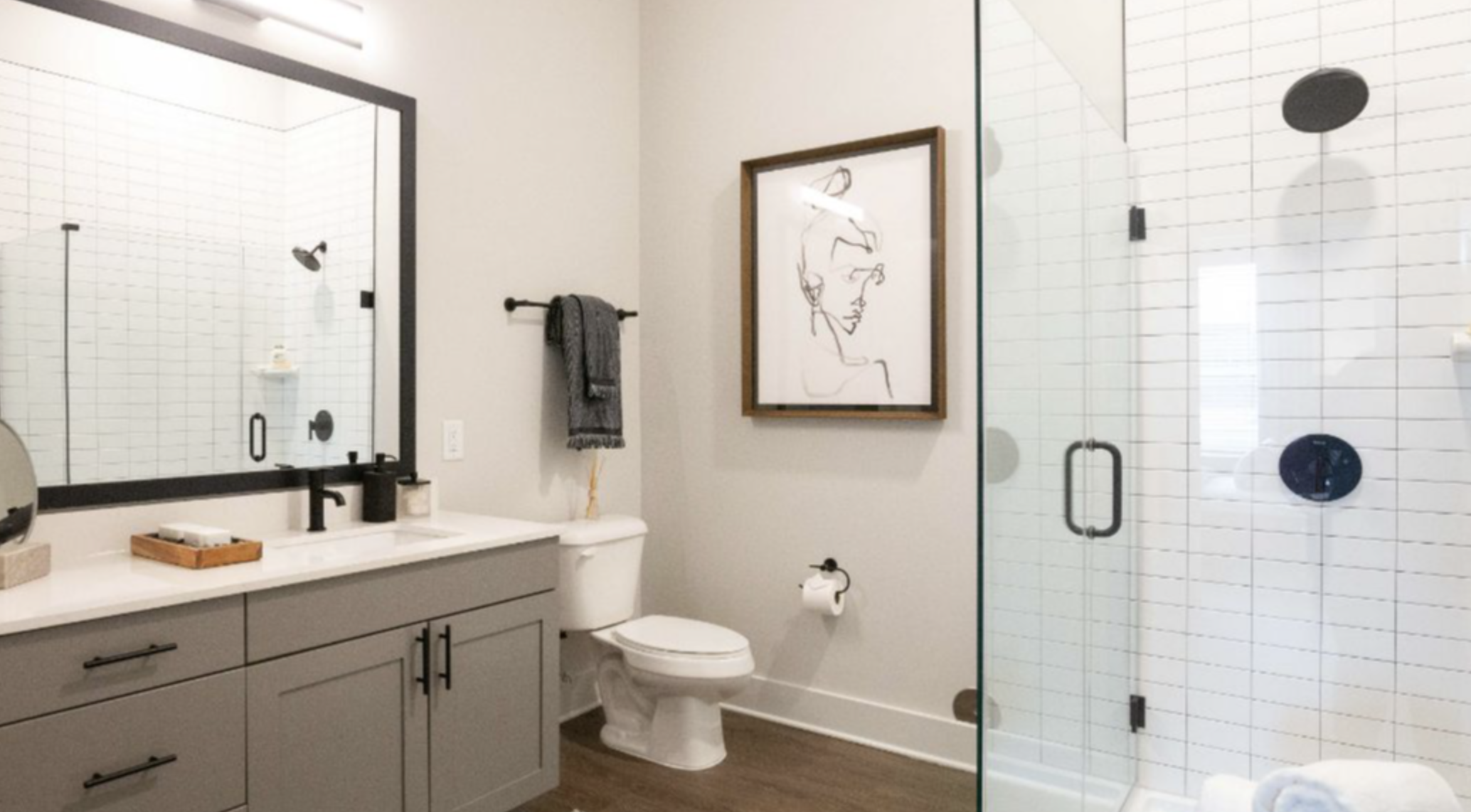 Decatur apartment bathroom with grey cabinets and a walk in shower.
