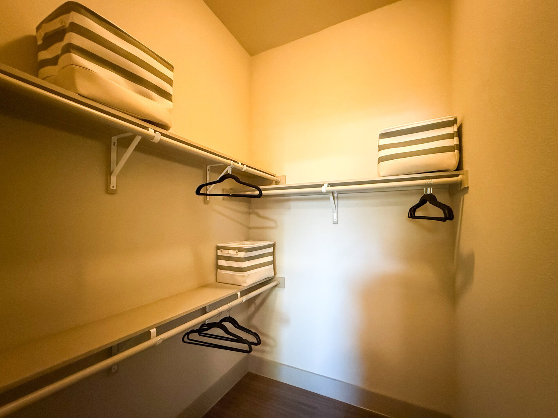 A small closet features two shelves and ample space for additional items.