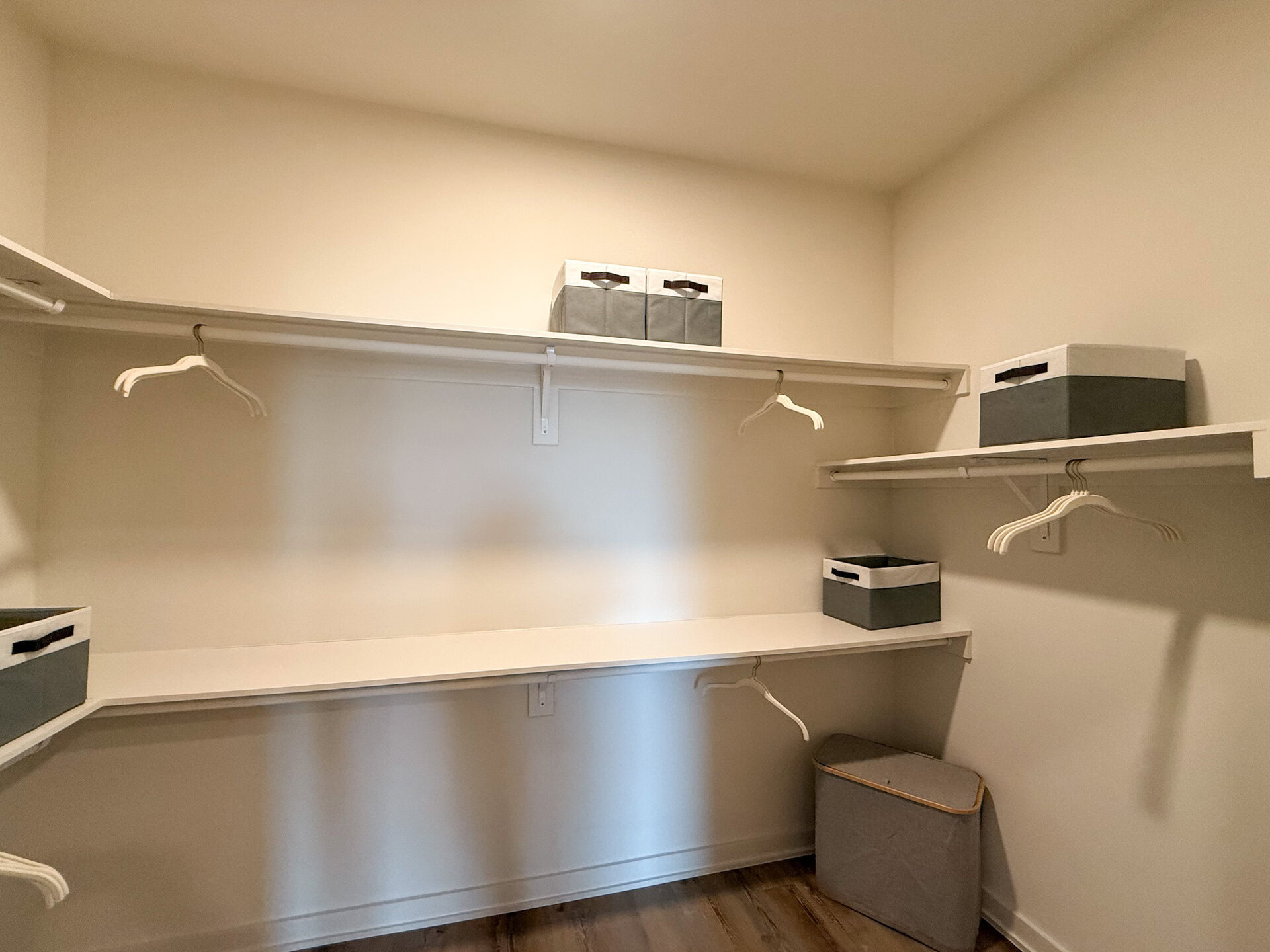 A very spacious closet features white shelving and several white shelves.