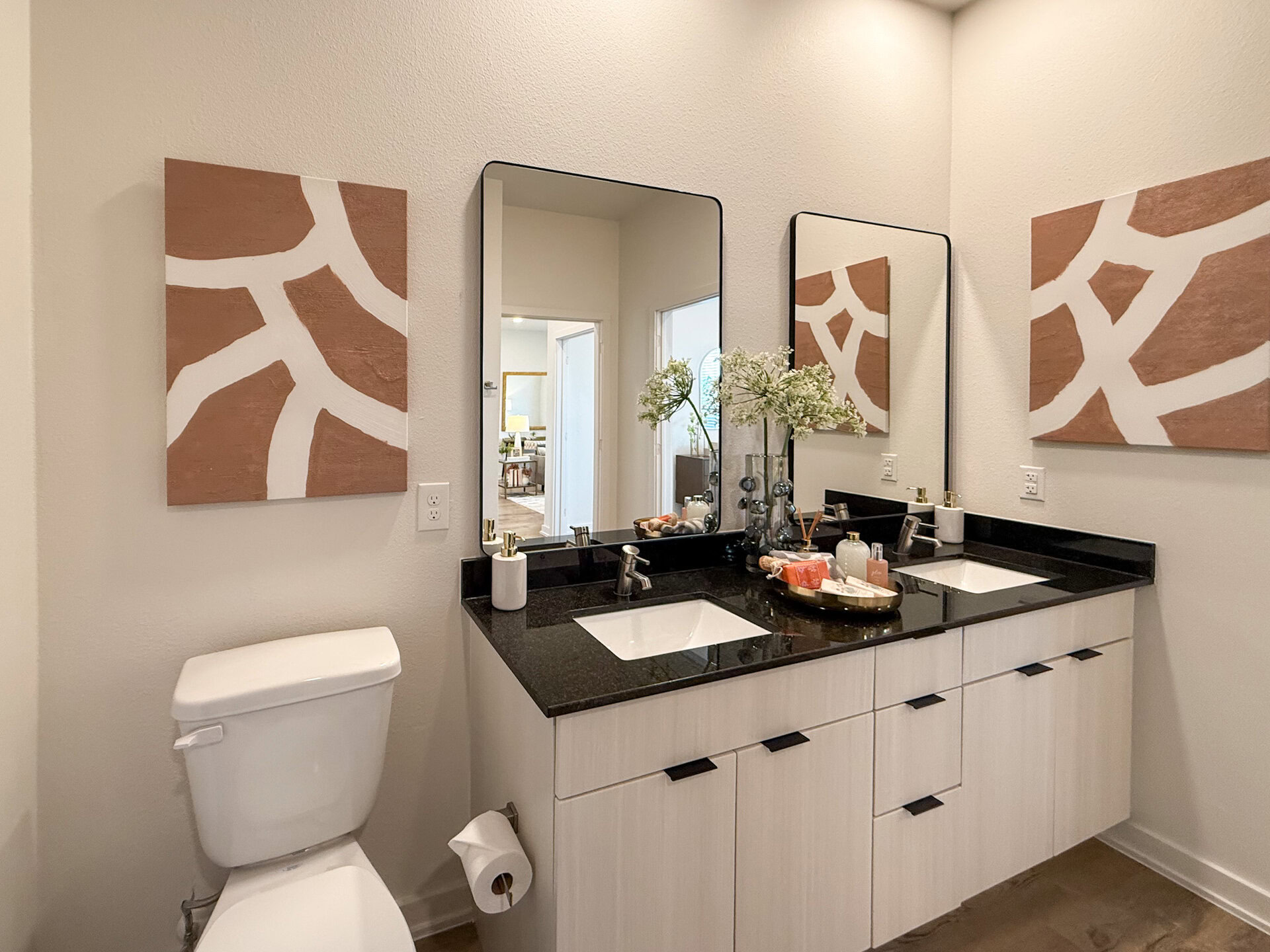 A modern bathroom features a double vanity with a sleek black countertop and two square sinks.