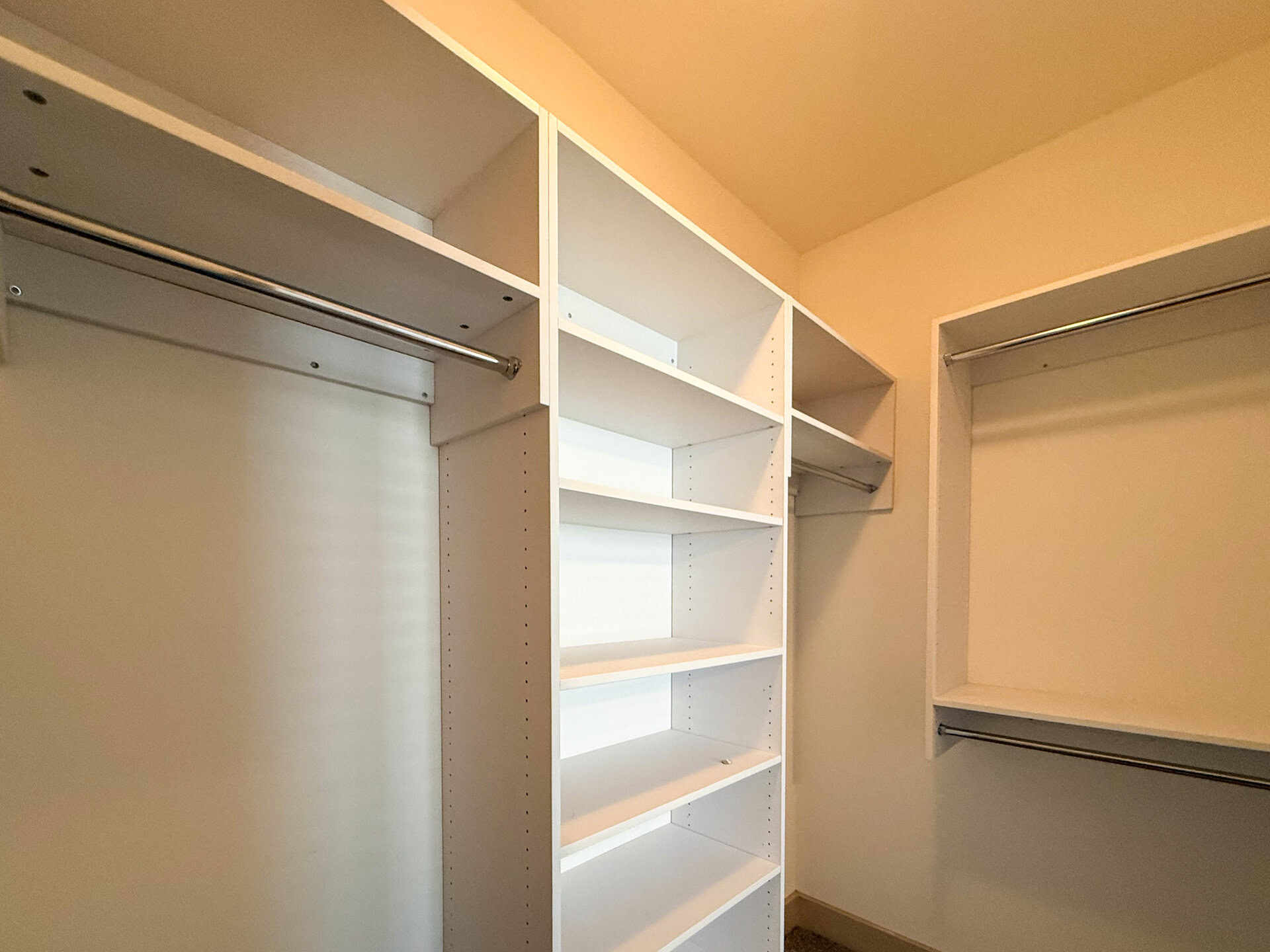 A well-organized closet space featuring white shelving units and hanging rods.