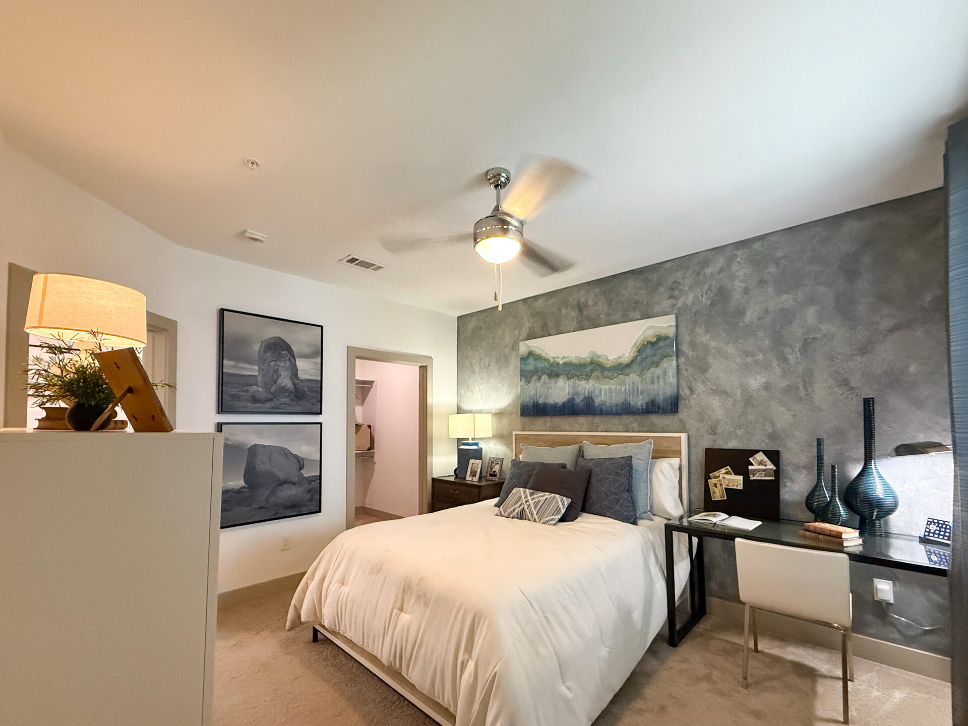 A modern San Antonio apartment secondary bedroom features a bed. A doorway leads to a closet area.