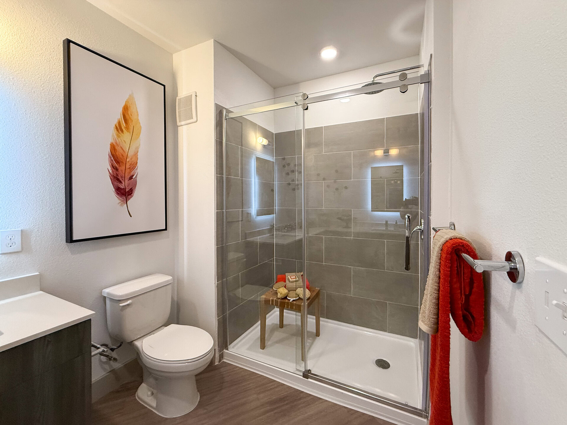 A San Antonio apartment modern bathroom features a glass shower enclosure with gray tiled walls.
