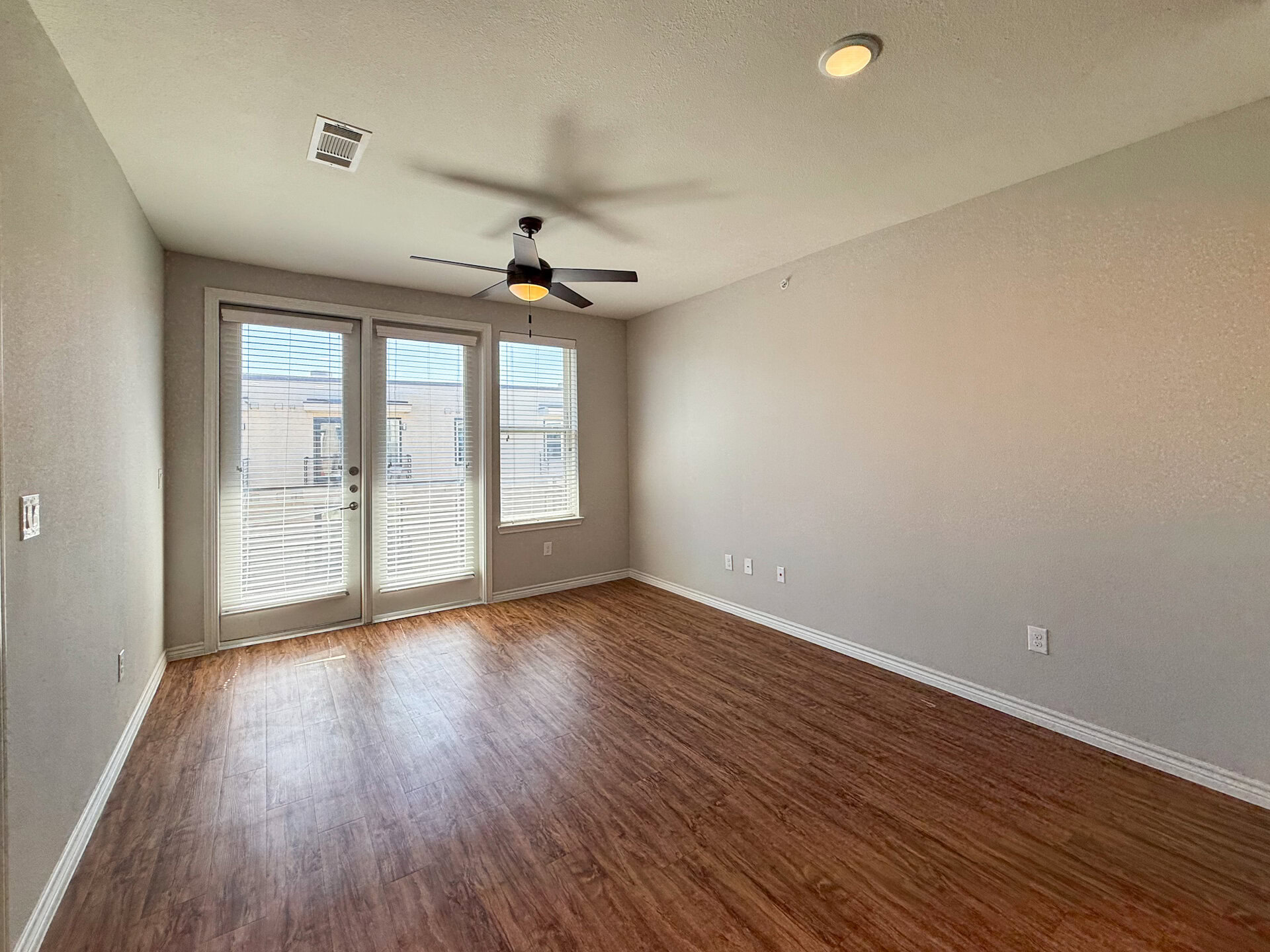 San Antonio modern apartment with a spacious living room features a light floors and neutral-colored walls. Balcony leads out to city view.