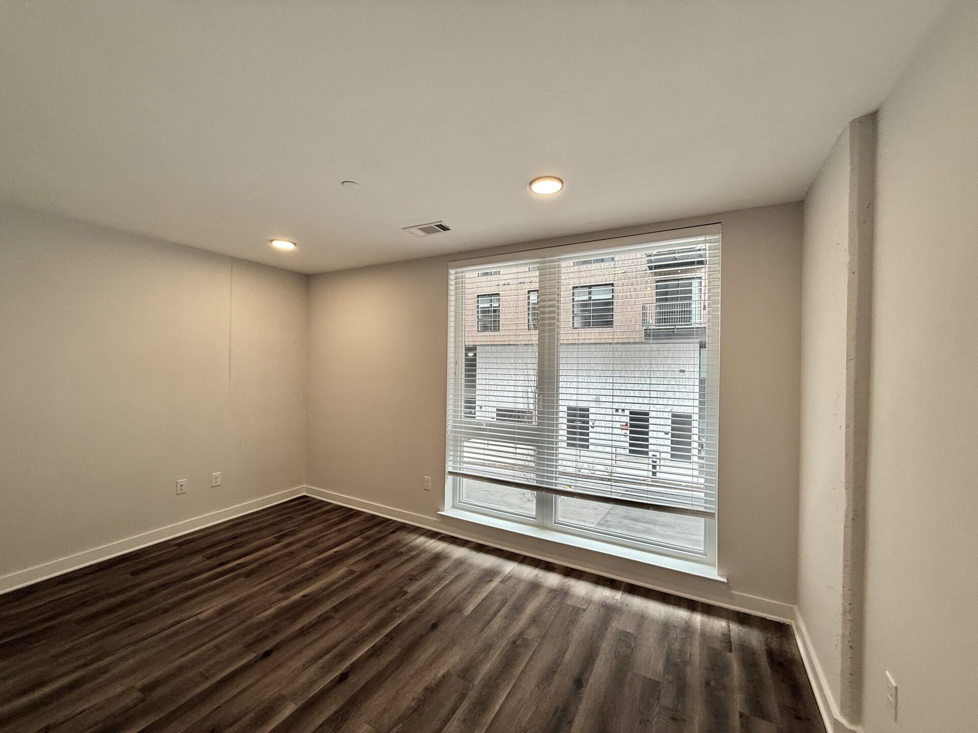 Apartments in Downtown Nashville, bedroom with a large window and wood floors.