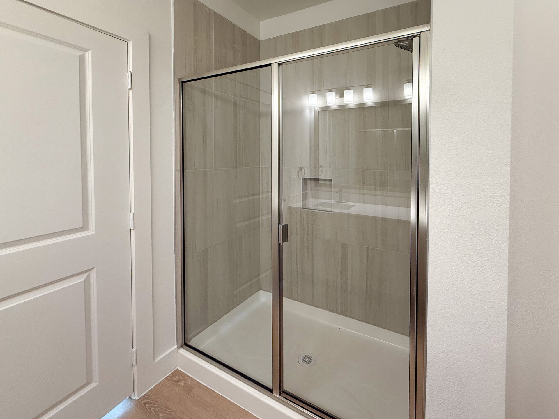 A modern San Antonio apartment with a glass-enclosed shower. The interior showcases light-colored, textured tiles that create a clean and contemporary look.