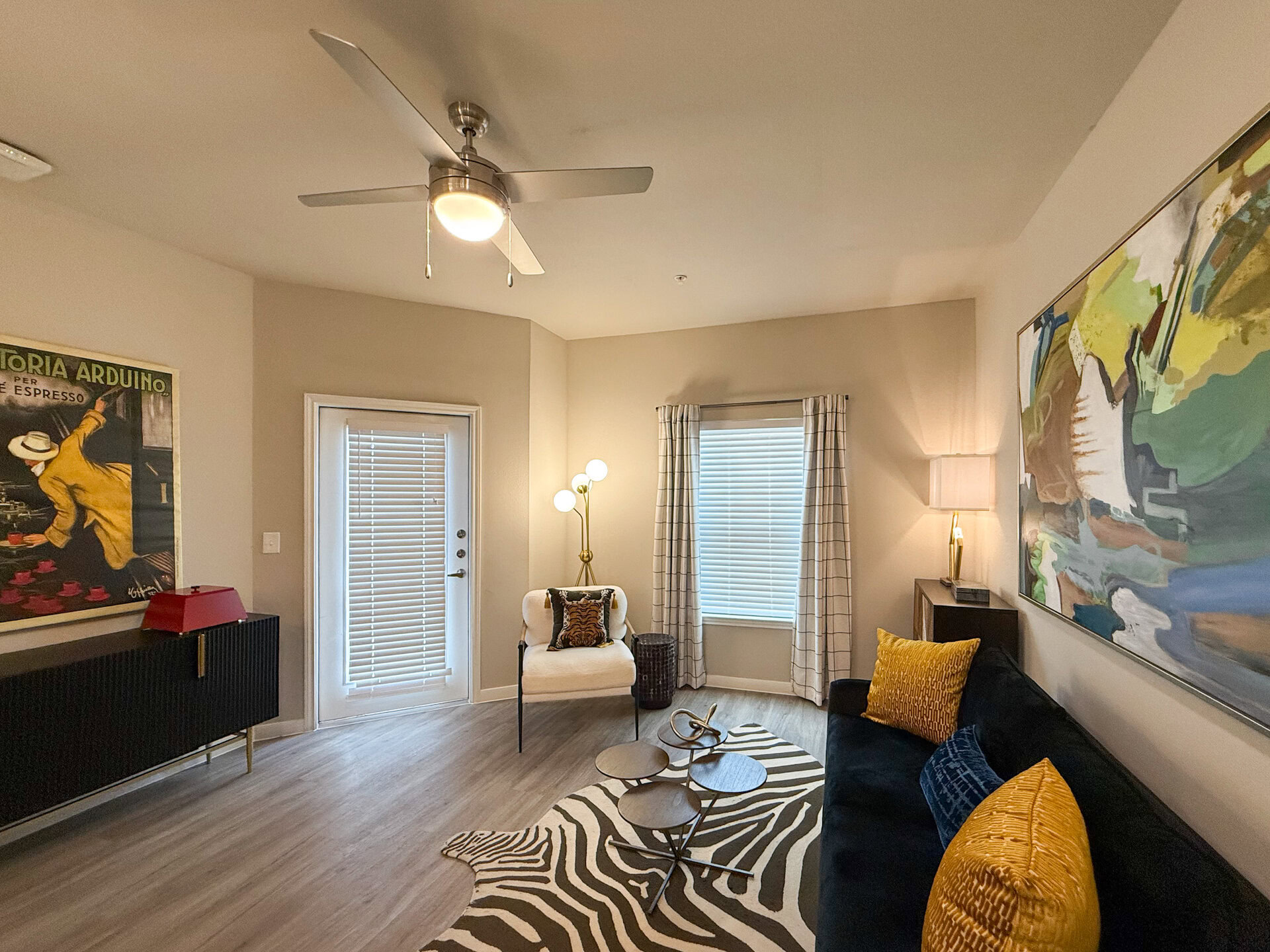 A cozy San Antonio apartment living room features spacious live space. Natural light streams in through the window, complemented by light-colored curtains.