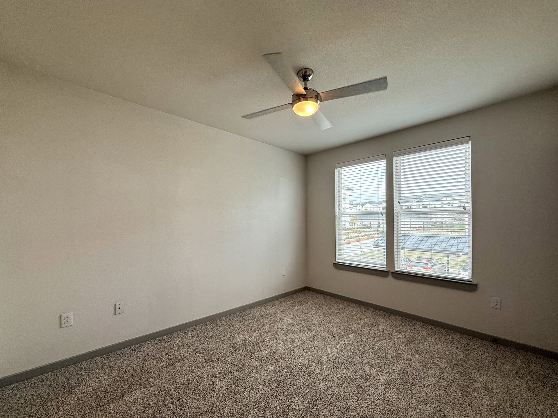 A spacious San Antonio apartment bedroom features carpet & ample sunlight coming in through the window.