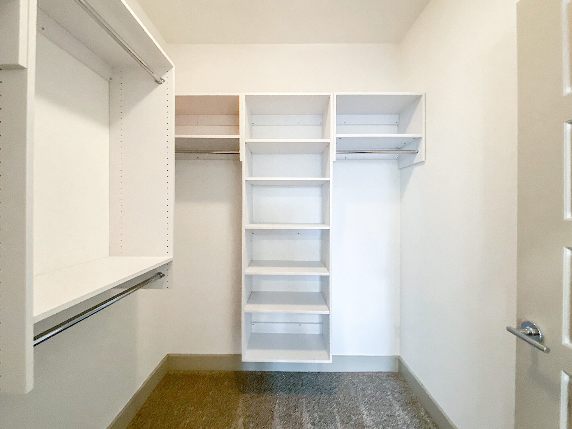 A spacious Northwest San Antonio loft apartment closet features white shelving and hanging rods.