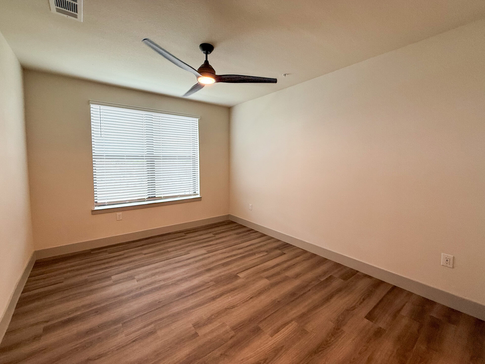 A San Antonio apartment spacious bedroom with a big window for plenty of natural sunlight to stream through & no carpet.