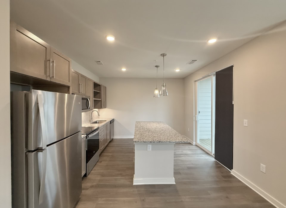 Nashville Apartment kitchen with a large island, brown wood cabinets, and stainless steel appliances.