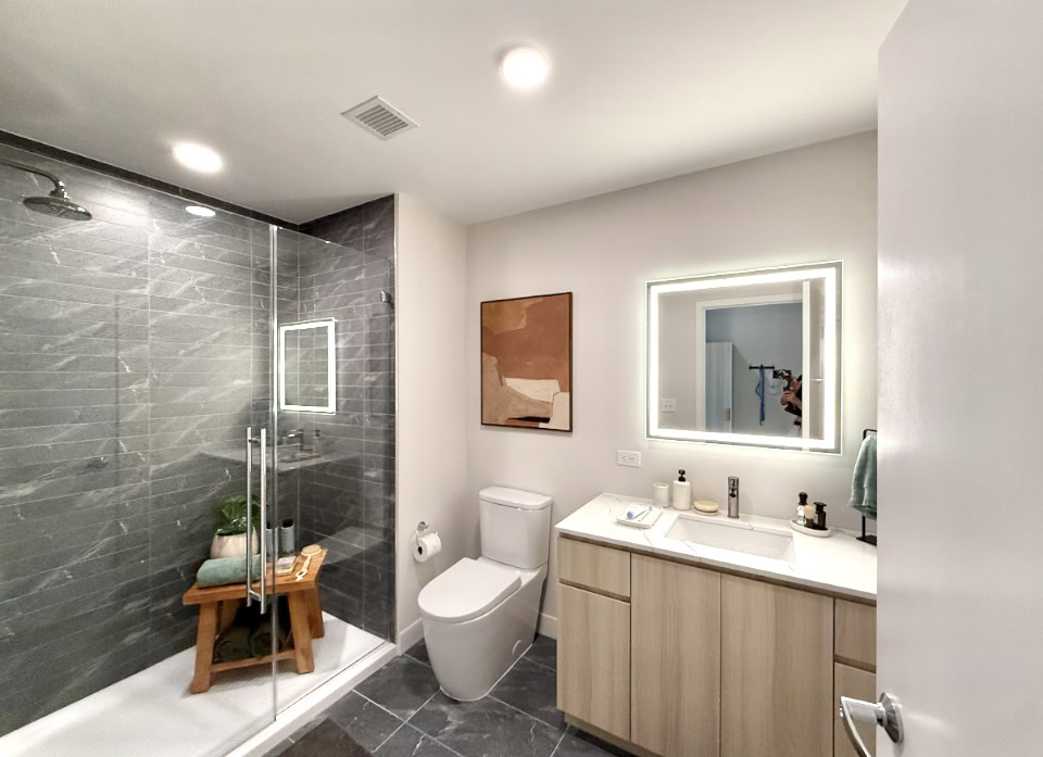 Nashville Apartment bathroom with a large walk-in shower. light wood cabinets, and and LED mirror.